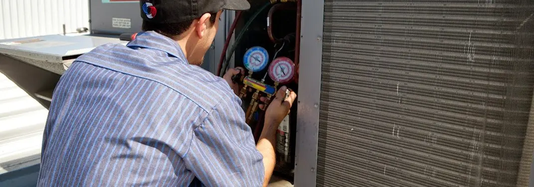 HVAC technician servicing a condenser unit in Westgate